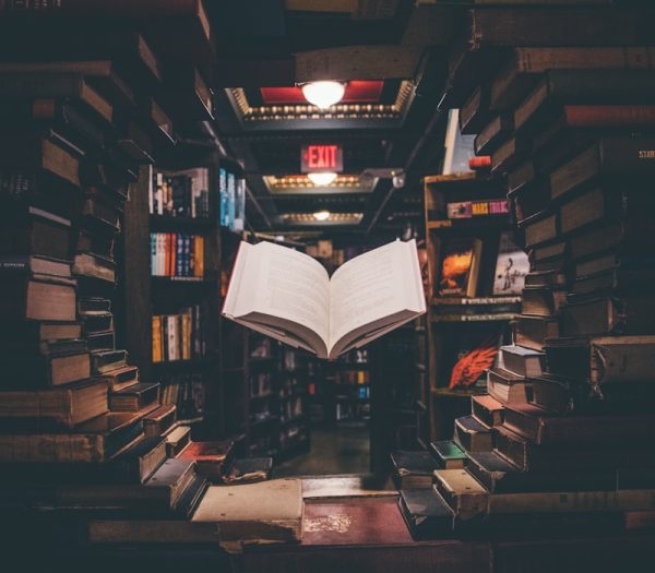 view of floating open book from stacked books in library